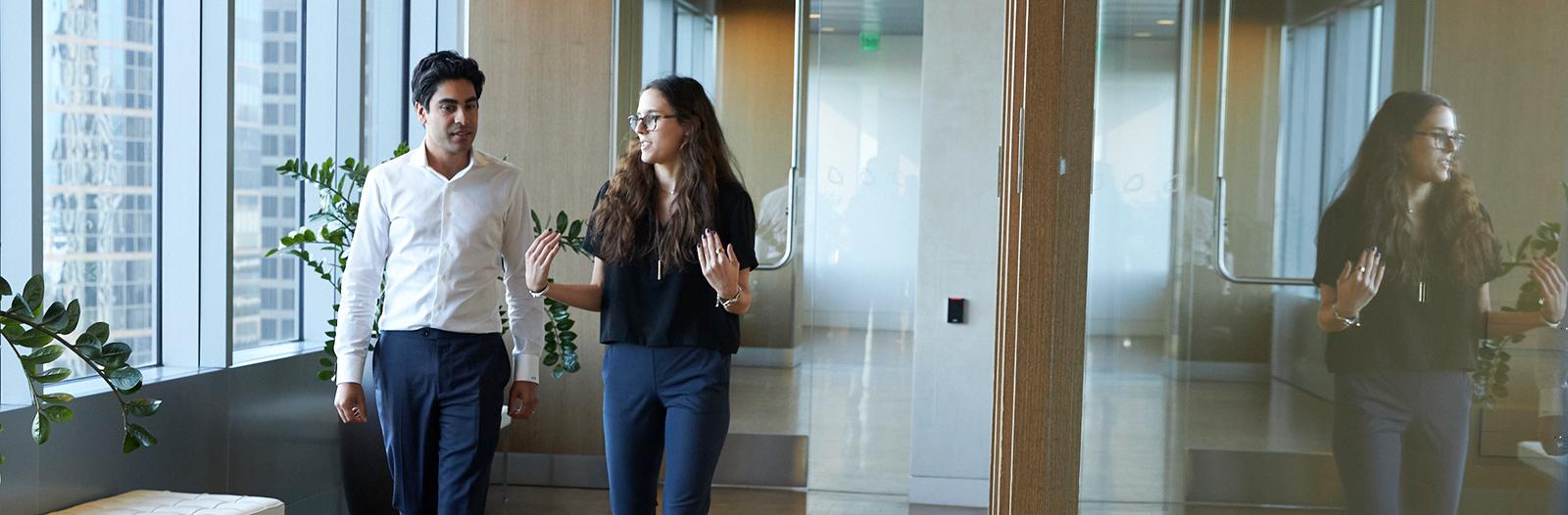 Two professionals discussing while waling in a corridor
